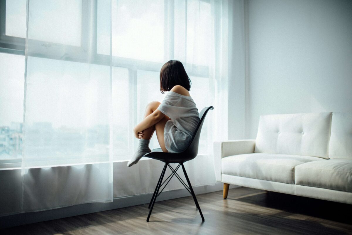 椅子の上に体育座りする女性の後ろ姿