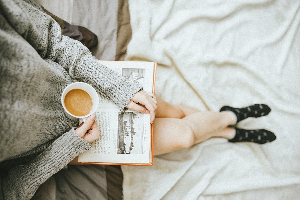 コーヒーを片手に本を読む女性
